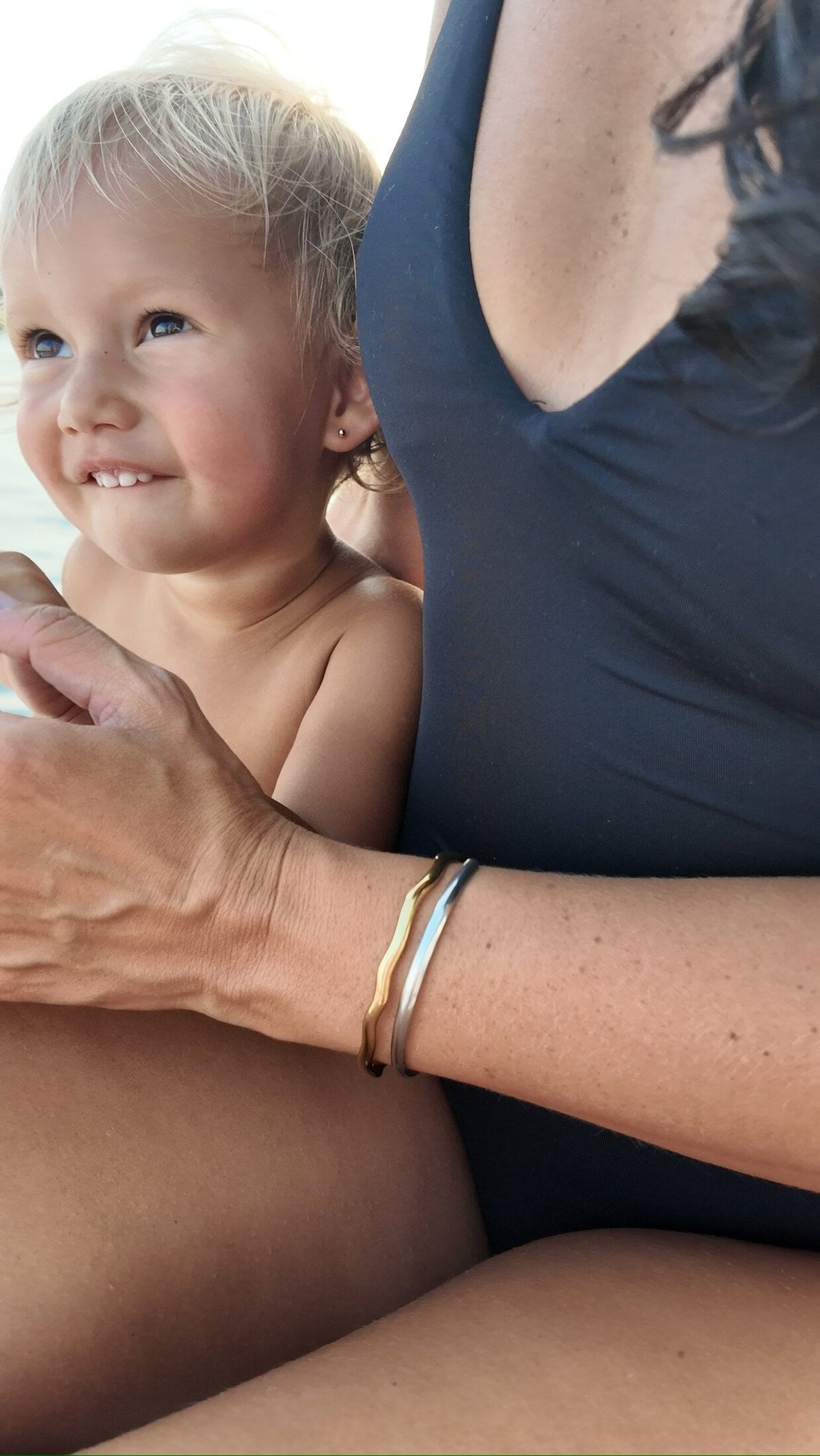 Mother and toddler both wearing Penny Faye bangles on a boat