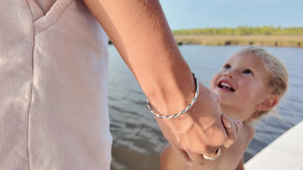 Mother holding toddler's hand, both wearing matching bangles